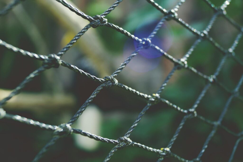 A detailed close-up of a wire fence outdoors with artistic bokeh effect.