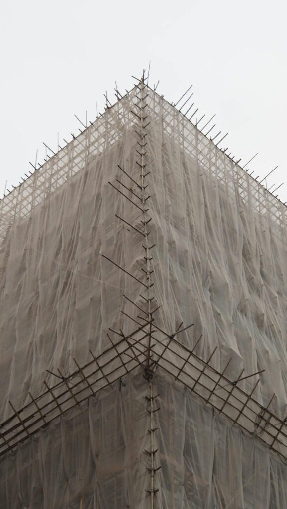 A detailed view of a building corner covered with scaffolding, showcasing urban construction.
