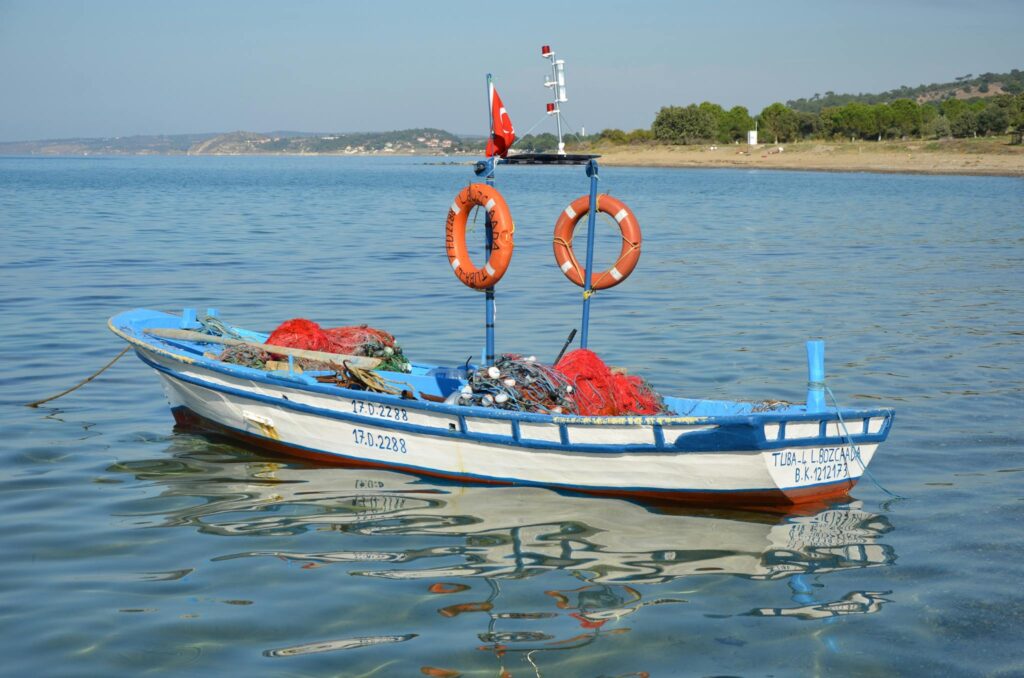 A vibrant fishing boat with nets moored in Geyikli, Turkey, during summer.